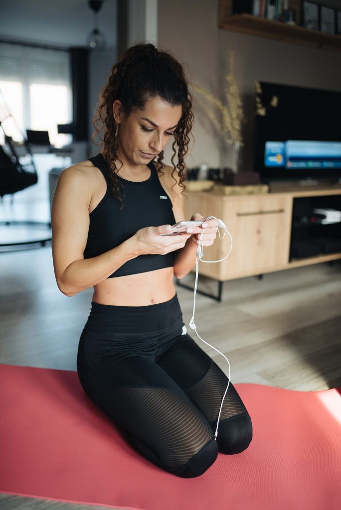 A Woman Kneels On A Yoga Mat In A Cozy Living Room, Focused On Her Sma — Sports & Fitness | RESIMLAND